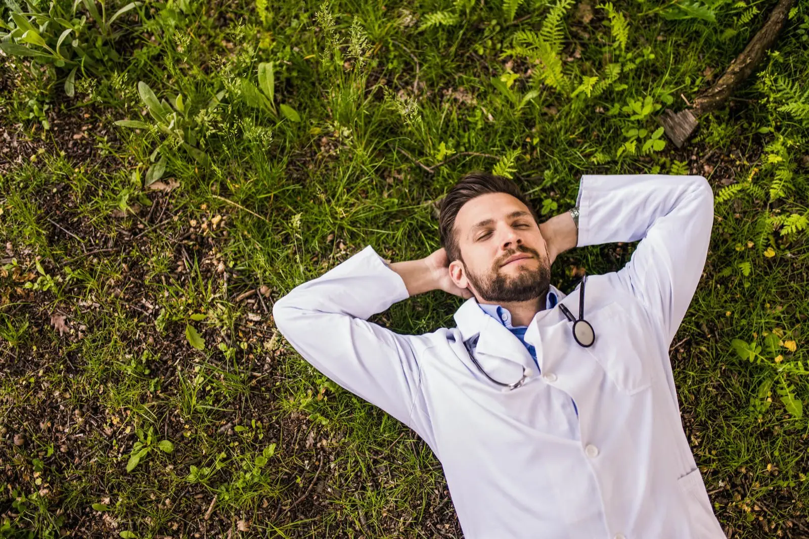 A doctor lying back in the grass, completely at ease