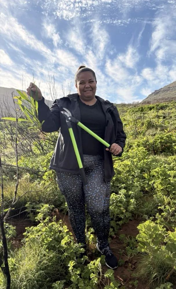 A team member holding up a cleared sapling and loppers