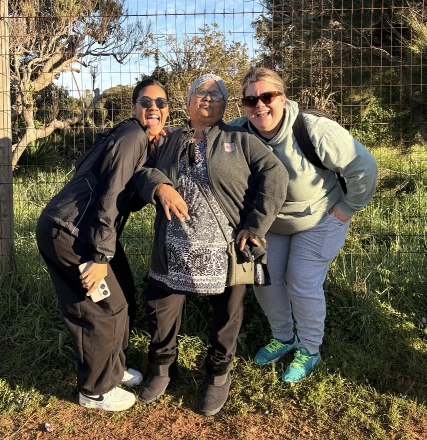 Three team members laughing at the fence line on Mandela Day