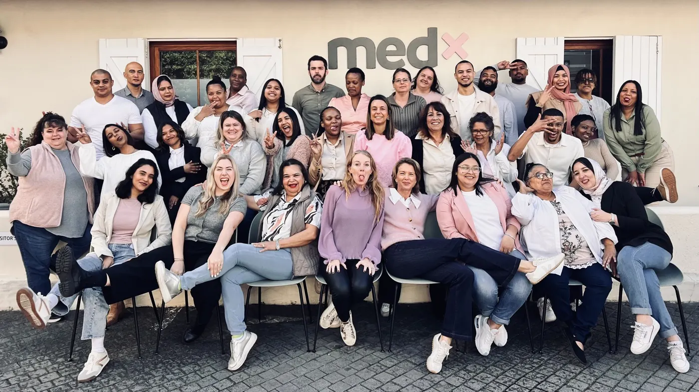 The whole MedX team goofing around in front of the medx sign