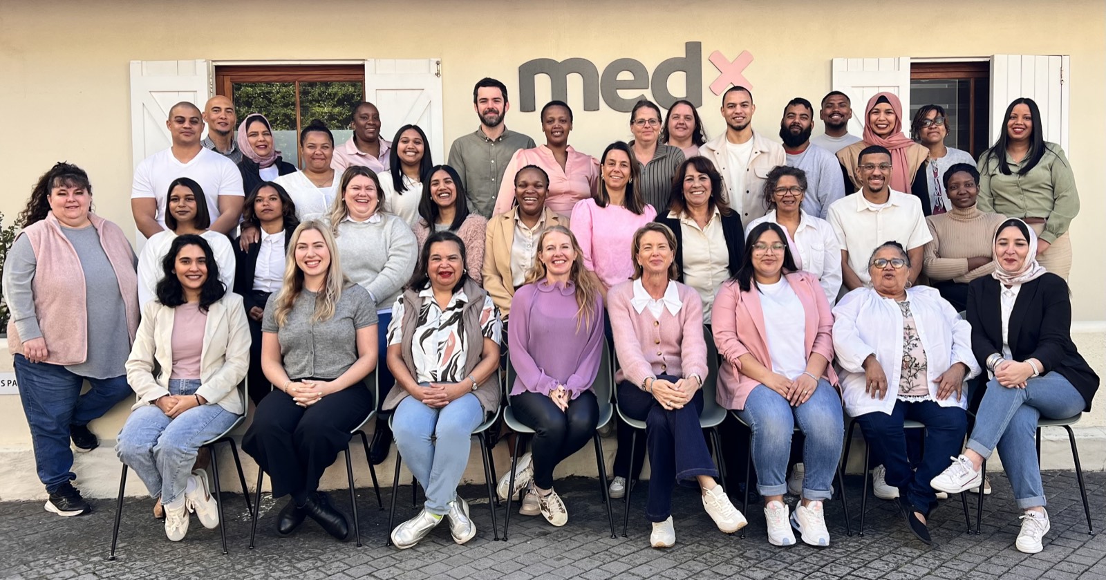 The whole MedX team in front of the medx sign at the Claremont office
